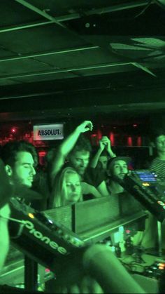 a group of people standing around each other in a room with dj equipment on the floor