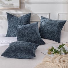 three blue pillows sitting on top of a bed next to a blanket and pillow case