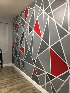 the wall is decorated with grey and red geometric designs on it, along with a black chair