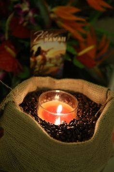 a lit candle sitting in a sack filled with coffee beans