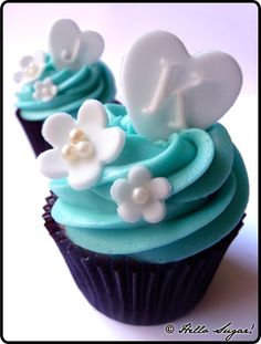 two cupcakes with blue frosting and white flowers