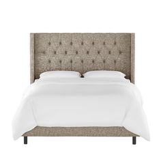 an upholstered bed with white linen and buttons on the headboard is shown