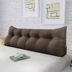 a white bed with a brown headboard and pillows on it next to two framed pictures