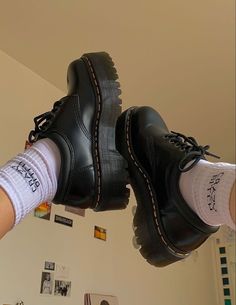 a pair of black shoes hanging from the ceiling with white socks on top of them