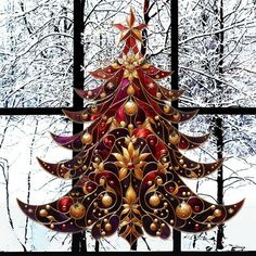 a stained glass christmas tree hanging in front of a window with snow covered trees behind it