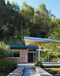 a house in the middle of a wooded area with trees and bushes around it,