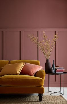 a living room with pink walls and orange furniture in the corner, including a yellow couch