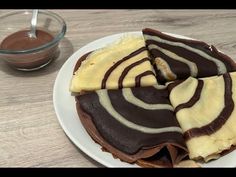 there is a chocolate cake with white frosting on the plate next to a bowl of chocolate