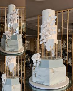 three tiered wedding cake with white flowers on top and blue ribbon around the bottom