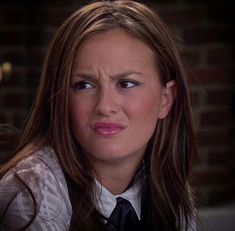 a woman wearing a white shirt and black tie looking at the camera with an angry look on her face