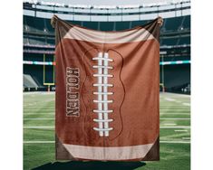 a football themed towel hanging on the sideline of a football stadium with an empty field in the background