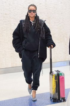 a woman with dreadlocks is pulling a suitcase and carrying it through an airport