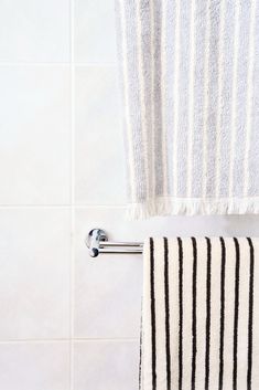 a towel is hanging on the wall next to a bathtub with a striped towel