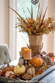 a table topped with lots of different types of fall decorations and candles on top of it