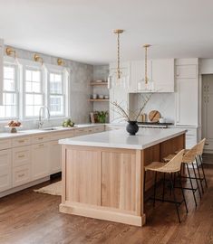 a large kitchen with white cabinets and wooden flooring is featured in this article by the interior design magazine