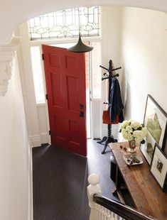 an entryway with a red door and wooden bench