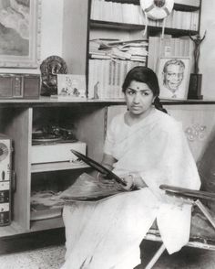 an old photo of a woman sitting in a chair holding a piece of paper and looking at the camera