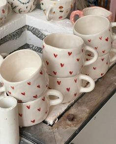 many white cups with red hearts on them are sitting on a table next to each other