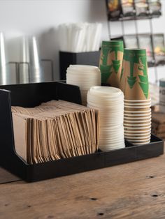 coffee cups and napkins are sitting on a wooden table in front of the disposable cup holders