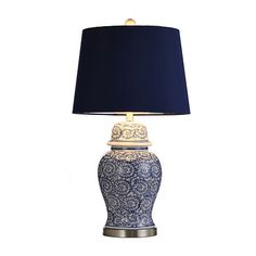 a blue and white table lamp with a black shade on the top, against a white background