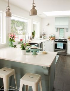 a kitchen with two stools in front of the counter and an island that has flowers on it