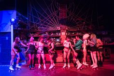 a group of young women standing around each other on roller skates in a bar