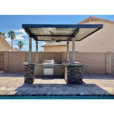 an outdoor bbq with grill and table next to a swimming pool