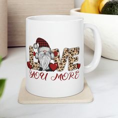 a white coffee mug with the words love you more on it and a santa clause hat