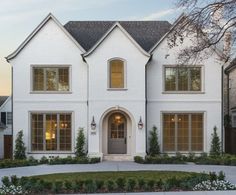 a white two story house with lots of windows on the front and side of it