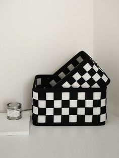 two black and white checkered baskets sitting on top of a table next to a can