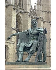 a statue of a man sitting on top of a bench in front of a building