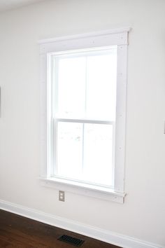 an empty room with white walls and wood flooring on the far wall, there is a window in the corner