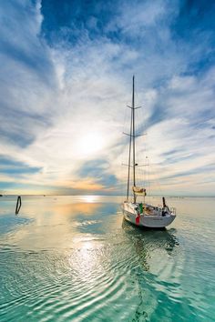 a sailboat floating in the ocean at sunset