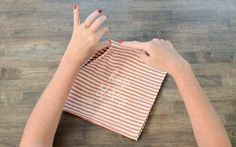 a woman's hands on top of a red and white striped paper bag that says, i am sorry