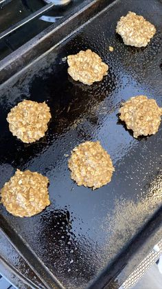 four hamburger patties are being cooked on a grill top with oil and grease over them