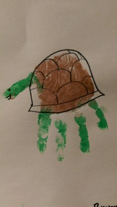 a child's handprint drawing of a turtle on white paper with green paint