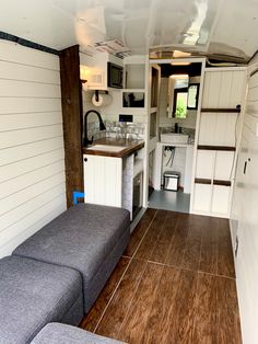 the interior of an rv with wood flooring and white walls, including a kitchen