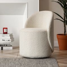 a white chair sitting on top of a wooden floor next to a potted plant