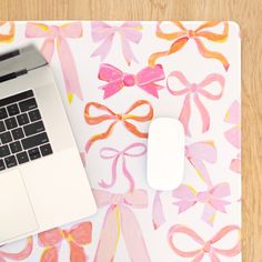 a laptop computer sitting on top of a desk next to a mouse and pink ribbon