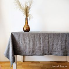 a table with a vase on it and a cloth draped over the top that has dried grass in it