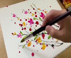 a person is using a marker to draw flowers on paper with colored pencils and watercolor paints