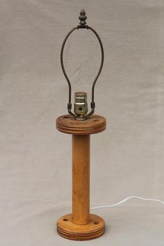 an old fashioned wooden lamp with a metal holder on it's base and a wire running through the top