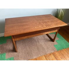 a wooden table sitting on top of a carpeted floor next to a potted plant