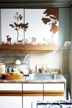 a kitchen with a sink, dishwasher and wall decals on the walls