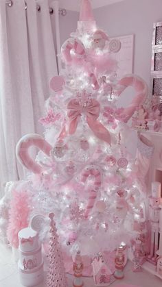 a pink and white christmas tree decorated with candy canes, candies, bows and more