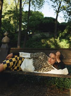 a woman laying on top of a wooden bench