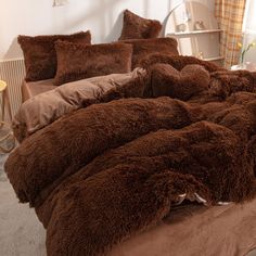 a bed covered in brown fluffy blankets and pillows