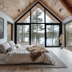 a large bed sitting inside of a bedroom next to a wooden floor covered in pillows