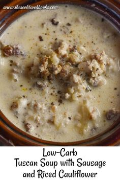 a bowl of soup with sausage and red cauliflower in it on a table