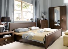 a bed room with a neatly made bed next to a dresser and chair in front of a window